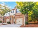 Two-story townhome with a brick facade, attached garage, and a quaint front porch at 2735 Sudbury Trce, Norcross, GA 30071