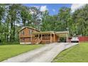 Exterior shot of home with long driveway featuring wood siding, and a covered carport at 860 The Cir, Lawrenceville, GA 30043