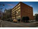 Nighttime view of a brick building on a city street with parked cars and pedestrians nearby at 800 Peachtree Ne St # 8607, Atlanta, GA 30308