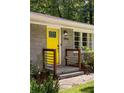 Close-up of the bright yellow front door and entryway with modern railing at 2041 Trailwood Rd, Decatur, GA 30032