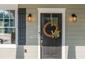 Close-up of the front door with decorative wreath, stylish lighting, and black shutters at 176 Olympic Pl, Decatur, GA 30030