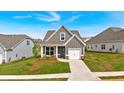 New construction single-Gathering home featuring an attached garage, cozy front porch with a chair, and lush green lawn at 71 Colonial Terrace, Villa Rica, GA 30180