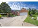 Brick home featuring an attached two-car garage and driveway, surrounded by green lawn at 3946 Village Crossing Ln, Ellenwood, GA 30294