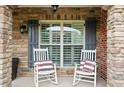Charming front porch with stone columns featuring two white rocking chairs and striped pillows at 4435 Manor Creek Dr, Cumming, GA 30040