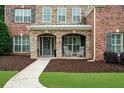Inviting covered front porch with stone arches and rocking chairs for relaxing and enjoying the outdoors at 4435 Manor Creek Dr, Cumming, GA 30040
