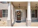 Charming front entrance with a decorative fall wreath, sidelights, and brick columns at 6861 Louis Dr, Locust Grove, GA 30248