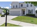 View of a lovely gray two-story home with a well-manicured lawn, and a two-car garage on a sunny day at 522 Evans Ln, Woodstock, GA 30188
