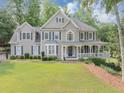 Charming two-story home features a spacious porch, manicured lawn and beautiful, mature trees at 1245 Smokehouse Trl, Cumming, GA 30041