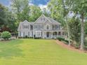 Charming two-story home features a spacious porch, manicured lawn and beautiful, mature trees at 1245 Smokehouse Trl, Cumming, GA 30041