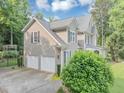 Side view showing two-car garage of charming two-story home surrounded by mature trees at 1245 Smokehouse Trl, Cumming, GA 30041