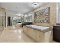 Luxurious bathroom features an elevated soaking tub, travertine walls and floors, a modern chandelier, and a mirrored wall at 3344 Peachtree Ne Rd # 3405, Atlanta, GA 30326