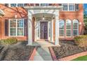 Close up of the front door of a red brick home with white columns and manicured landscaping at 608 Chickory Ct, Woodstock, GA 30188