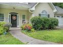 A welcoming home entrance with a black front door, colorful flower beds, and a concrete walkway at 1907 S Van Wert Rd, Villa Rica, GA 30180