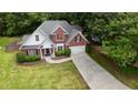 Aerial view of a two-story brick home with lush trees, a long driveway, and a well-manicured lawn at 1245 Grace Hadaway Ln, Lawrenceville, GA 30043