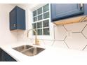 Close-up of kitchen sink area featuring white countertops, unique backsplash, and modern faucet at 935 Conley Se Rd, Atlanta, GA 30354