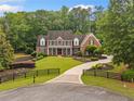 A charming two-story brick home features a manicured front lawn, black fencing, and a circular driveway at 325 Edwards Brook Ln, Canton, GA 30115