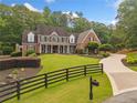 A beautiful two-story brick home boasts a manicured front yard, black fencing, and a circular driveway at 325 Edwards Brook Ln, Canton, GA 30115