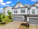 Two story townhome with a gray two car garage, and well landscaped front yard at 359 Crider Ct, Woodstock, GA 30188