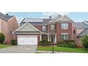 Charming two-story brick home boasts a well-manicured lawn, attached garage, and solar panels at 1489 Belmont Hills Dr, Suwanee, GA 30024