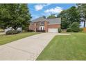 Beautiful brick home with a long driveway, lush green lawn, and mature trees, offering a serene setting at 285 Finsbury Park Ct, Suwanee, GA 30024