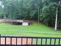 View of a large backyard with a wooded area and an outbuilding with an additional garage at 3964 Hamilton Mill Rd, Buford, GA 30114