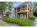 View of condominium exterior featuring wood balconies, a concrete sidewalk, and attractive shrubbery at 202 Berkeley Woods Dr, Duluth, GA 30096