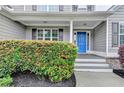 Charming front porch featuring a bright blue door surrounded by lush green bushes at 327 Oakland Bay Ct, Loganville, GA 30052