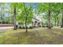 Exterior view of a charming white brick home nestled among lush trees and a well-maintained lawn at 3252 Custer Lake Drive Northwest Nw Dr, Marietta, GA 30064