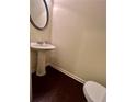 Small bathroom with pedestal sink, round mirror, and dark hardwood floors at 664 Oakside Pl, Acworth, GA 30102
