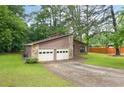 Home exterior features a two-car garage, wood siding, stone accents and a long driveway at 9383 Woodknoll Way, Jonesboro, GA 30238