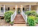 Inviting front porch with brick stairs, a white railing and lush landscaping at 2200 E Lake E Rd, Mcdonough, GA 30252
