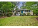 Beautiful house with light-colored siding, a blue front door, and a lush green lawn and mature trees at 4611 Dogwood Rd, Pine Lake, GA 30072