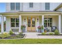 Inviting front porch with double doors, stylish seating, potted plants and classic white columns at 6168 Sweet Birch Ct, Acworth, GA 30101
