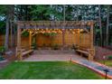 Charming backyard pergola with string lights, benches, and stone landscaping features for relaxation at 735 River Ridge Ln, Suwanee, GA 30024