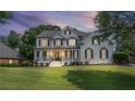 Elegant white brick home with covered porch and black shutters, beautifully lit during twilight at 735 River Ridge Ln, Suwanee, GA 30024