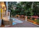Cozy outdoor deck featuring comfortable seating, string lights, and tranquil views of the surrounding trees at 735 River Ridge Ln, Suwanee, GA 30024