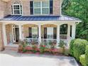 Inviting front porch featuring decorative columns, a cozy seating area, and beautiful blooming flowers at 4895 Smokestone Dr, Douglasville, GA 30135