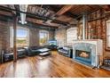 Living room with fireplace, hardwood floors, exposed brick, and large windows with city views at 490 Marietta St Nw # 307, Atlanta, GA 30313