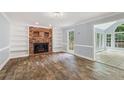 Living room with hardwood floors, fireplace, built-in bookcases, and view to sunroom at 4179 Westchester Ne Xing, Roswell, GA 30075