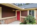 Inviting front entrance with a vibrant red door and brick accents surrounded by lush greenery at 49 Country Ct, Alpharetta, GA 30005
