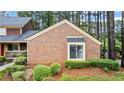 Close view of a brick townhouse surrounded by manicured landscaping and mature trees at 49 Country Ct, Alpharetta, GA 30005
