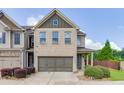 Inviting two-story townhome with brick accents, a two-car garage, and lush green shrubbery at , Lawrenceville, GA 30044