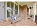 Welcoming front porch featuring a rustic wooden bench, brick flooring, and charming details at 3665 Pennington Rd, Cumming, GA 30041