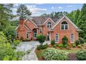 Attractive brick house featuring arched windows and a landscaped front yard with mature plantings at 119 Kennemer Ct, Johns Creek, GA 30097