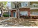 Inviting entrance with brick accents, a covered porch, and lush landscaping at 8020 Woodland Ln, Alpharetta, GA 30009