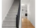 Carpeted staircase featuring a dark wood banister contrasted with light walls and hardwood floors at 90 Grove Park Ln, Woodstock, GA 30189