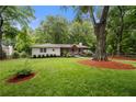 Quaint one-story house with a lush green lawn, mature trees, manicured landscaping and inviting covered front porch at 2020 New Kemp Rd, Marietta, GA 30066