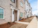 Townhome exterior showcasing brick facade, a covered entryway, and manicured landscaping at 3322 Cranston Ln, Kennesaw, GA 30144