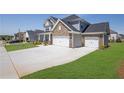Large driveway leading to a two-story home with a stone and vinyl facade and a 3-car garage at 307 Ernest Ave, Peachtree City, GA 30269