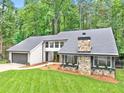 Beautiful exterior view with stone facade and grey siding nestled in a lush, wooded area at 2435 Roxburgh Dr, Roswell, GA 30076